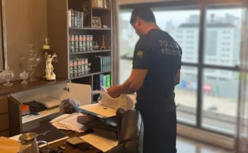 Agente da Polícia Federal examina documentos durante operação que investiga irregularidades na previdência dos servidores de Palhoça, em Santa Catarina.