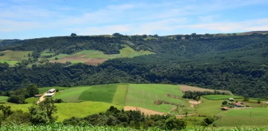 Paisagem rural com plantações, propriedades e morros cobertos por vegetação, usada para ilustrar o apoio do SC Rural 2 a agricultores e comunidades rurais de Santa Catarina.