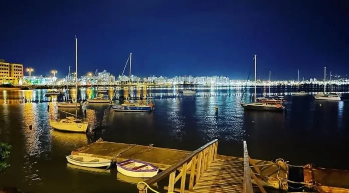 São José recebe 1ª Regata Plínio Verani de Veleiros de Oceano Veleiros ancorados à noite na Baía Sul, com luzes da cidade refletidas na água. Imagem ilustra a 1ª Regata Plínio Verani de Veleiros de Oceano, em São José.