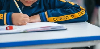 Estudante escreve em caderno durante atividade escolar; imagem ilustra o calendário de rematrículas e matrículas da Rede Municipal de Biguaçu para 2027.