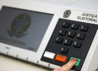 Eleitor pressiona a tecla confirma de uma urna eletrônica, em imagem que ilustra a suspensão da divulgação dos resultados das eleições pelo TSE após decisão do STF.